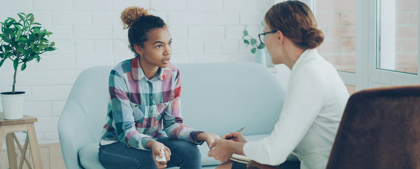 Healthcare provider speaking with a young patient in a supportive clinical setting